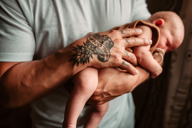 Newborn Photography, father laying baby across his arm