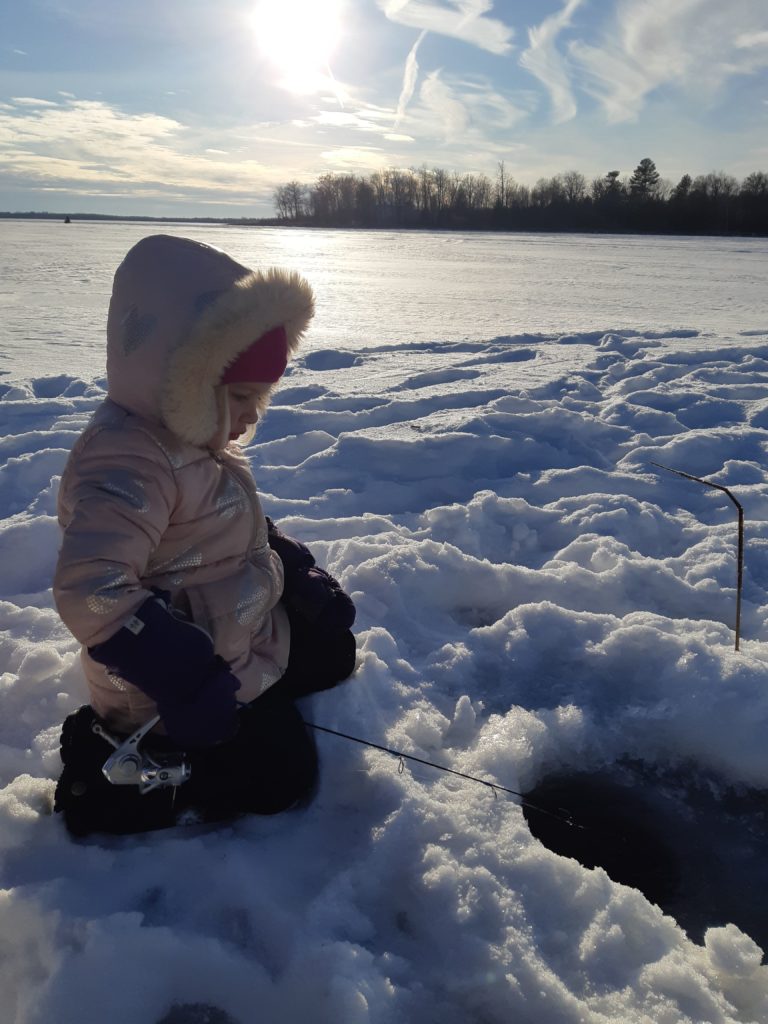 Young girl ice fishing on a lake on family day weekend in Durham