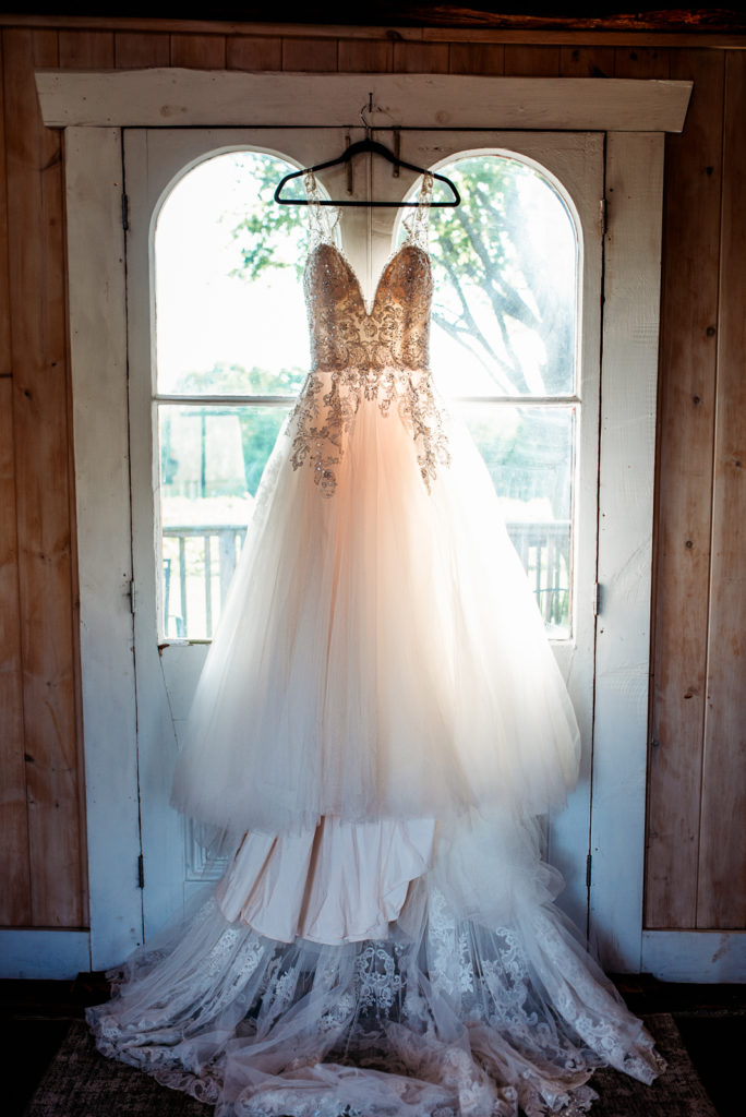 Wedding dress hanging in the doorway of a vineyard