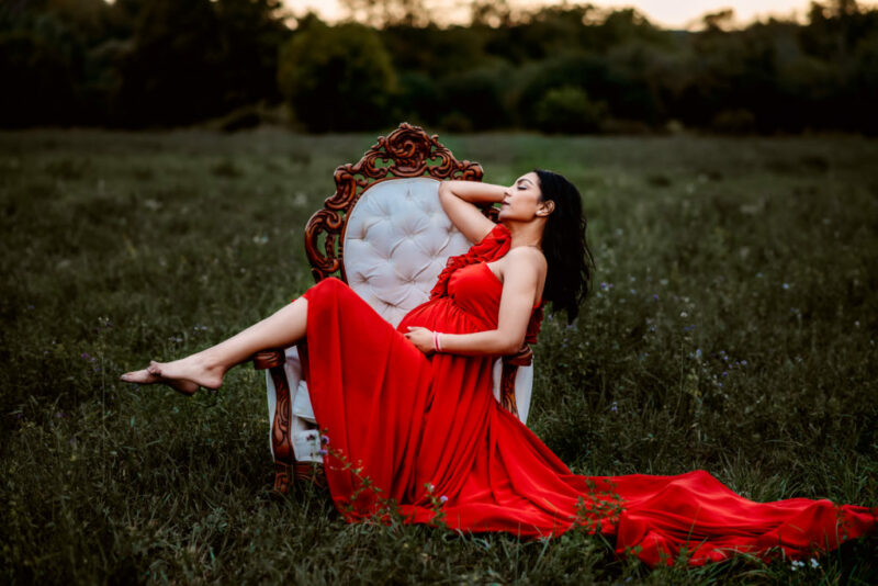 Pregnant woman lying on a white chair in a field during her peterborough maternity session