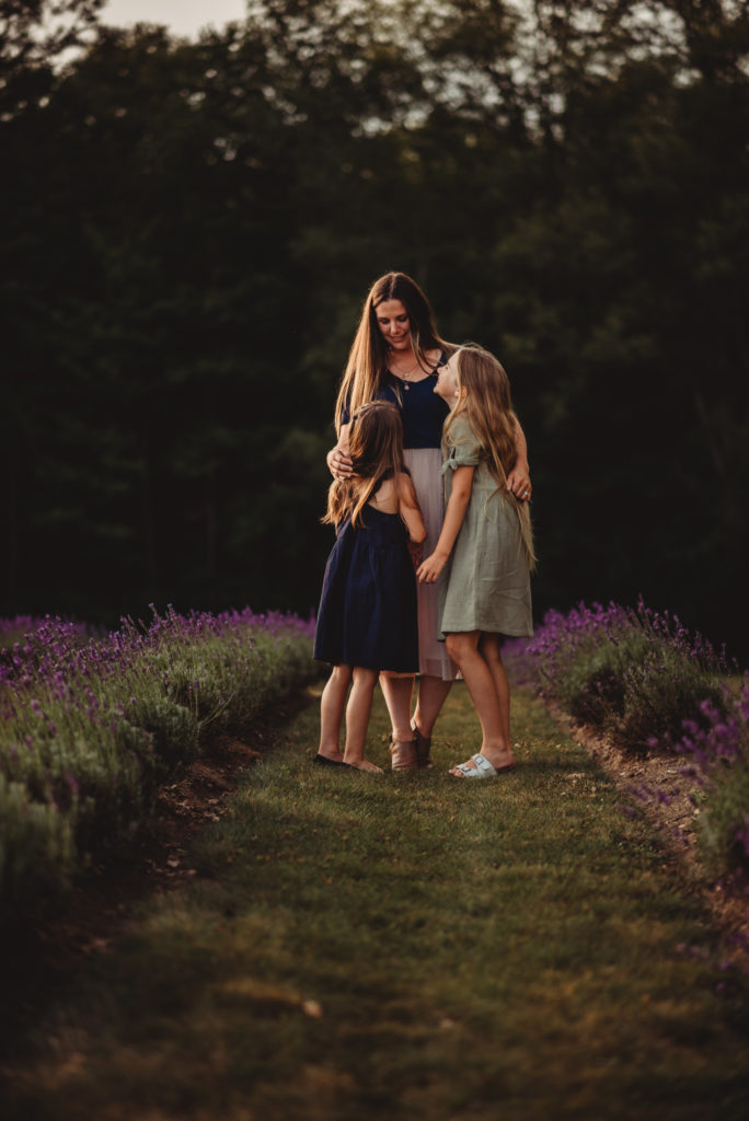 Mother looks down at her two daughters during a lavender photography session