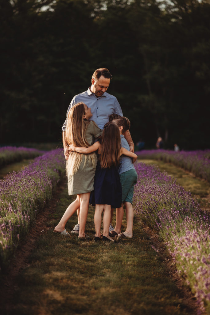 Father hugging his three children during a family photography session at laveanne lavender farm in port hope, ontario
