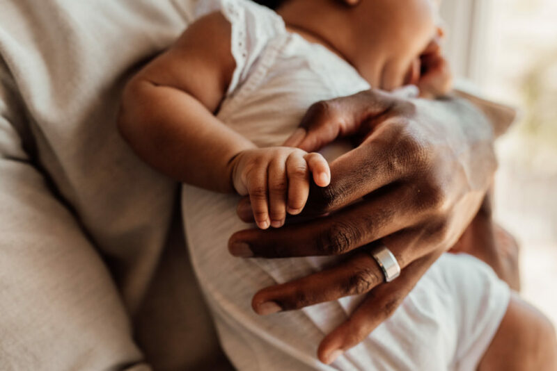 Close up of a baby holding her daddy's hand