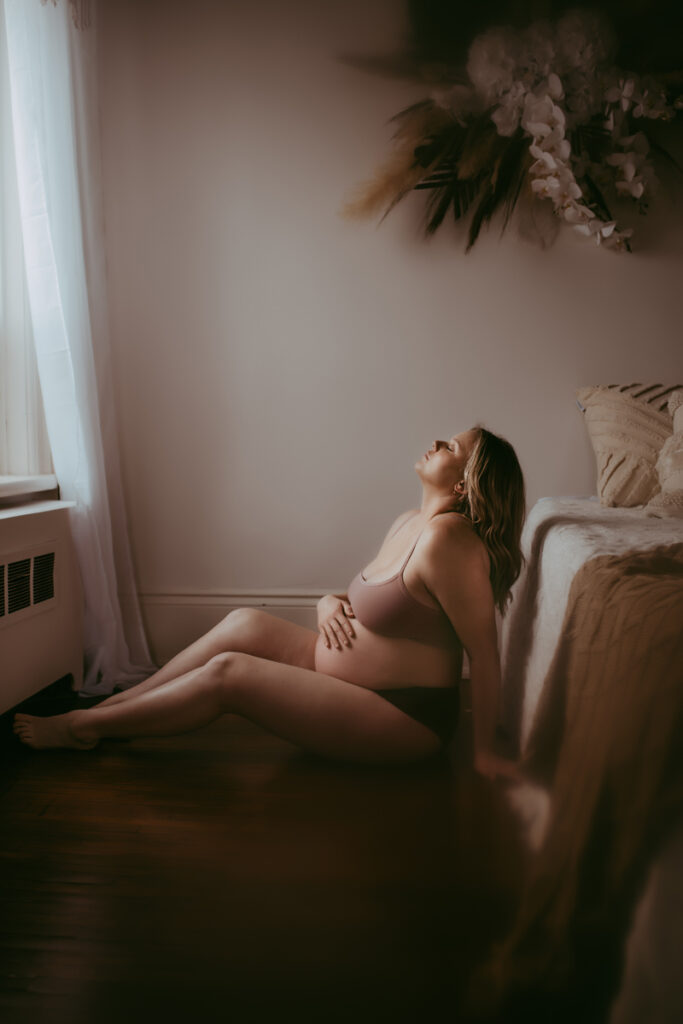 Maternity Photography, Mother sitting down with hand over her pregnant belly