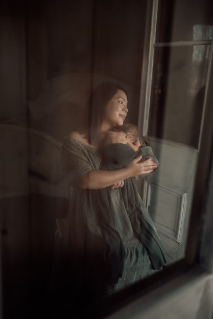 Reflection through a doorway of a new mother holding her newborn baby
