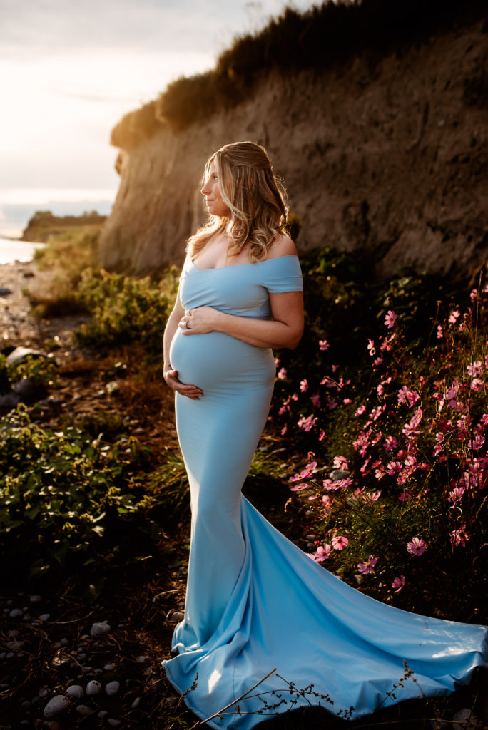 Oshawa maternity photography session showing a pregnant woman in a blue dress on the beach in Courtice