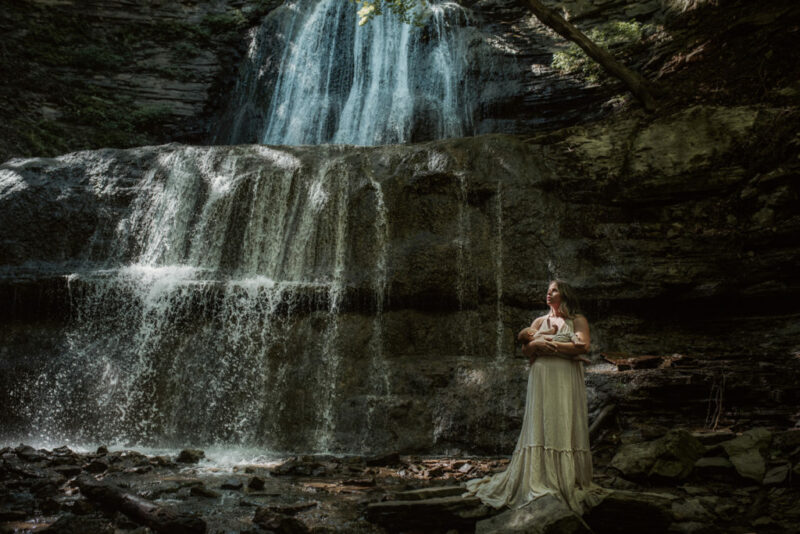 A mother holding her a baby during a hamilton waterfall newborn photography session