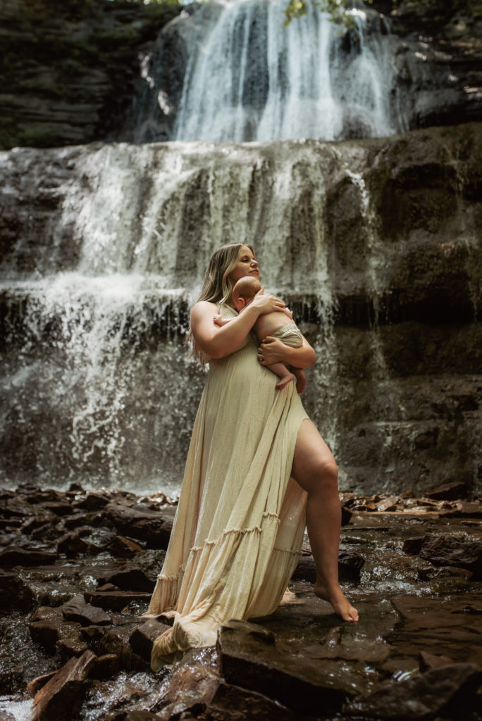 Mother holding her newborn baby in front of a Hamilton waterfall