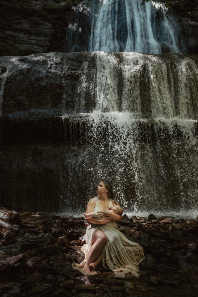 A new mother holding her newborn baby in front of a Hamilton Waterfall