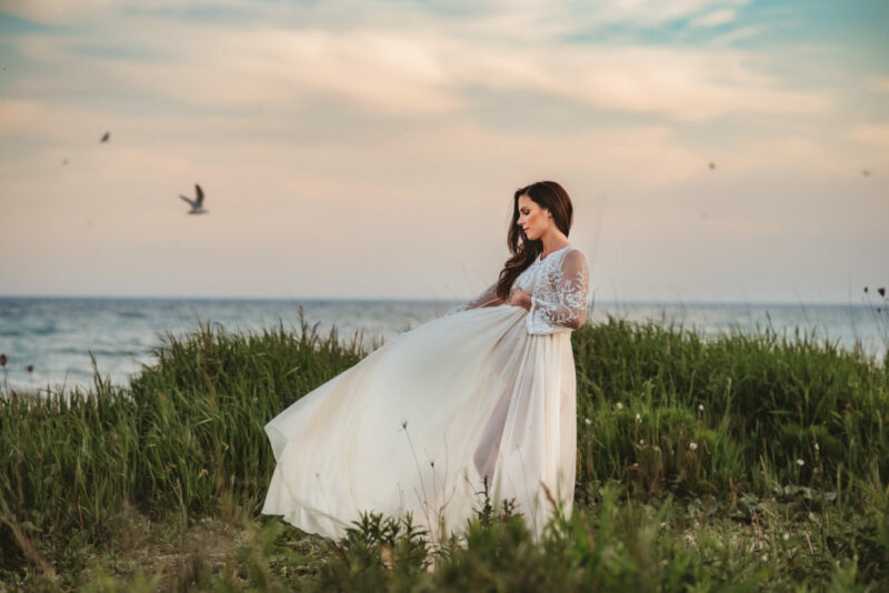 Pregnant woman in a white flowy dress at the beach in Oshawa