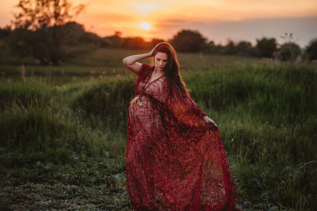 Pregnant woman in a field at sunset during a maternity photography session