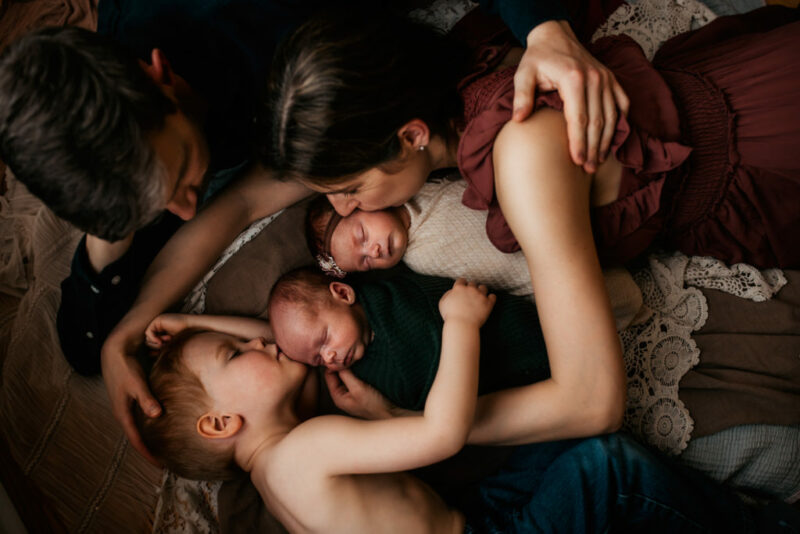 Family of five lying down around twin babies during a newborn photography session in Bowmanville