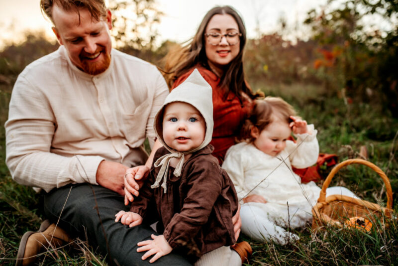 Family of four sitting in the grass in the fall
