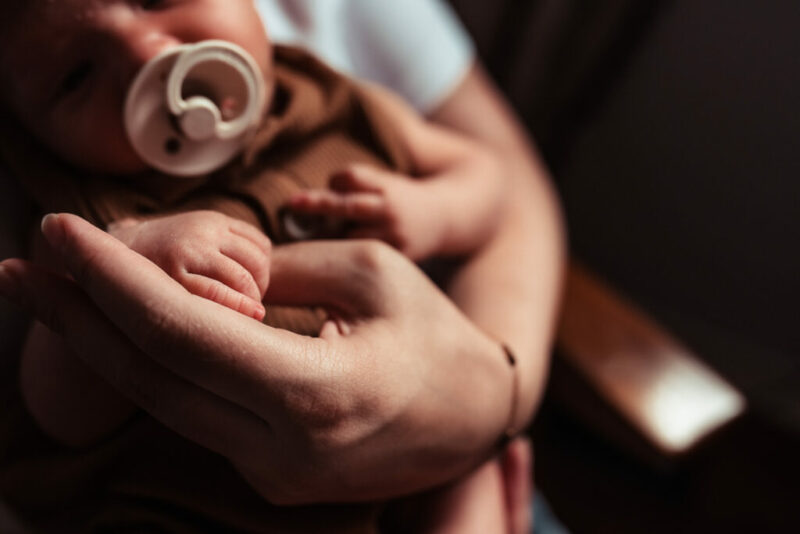 Close up of a mother holding her baby's hand during a whitby newborn photography session. 