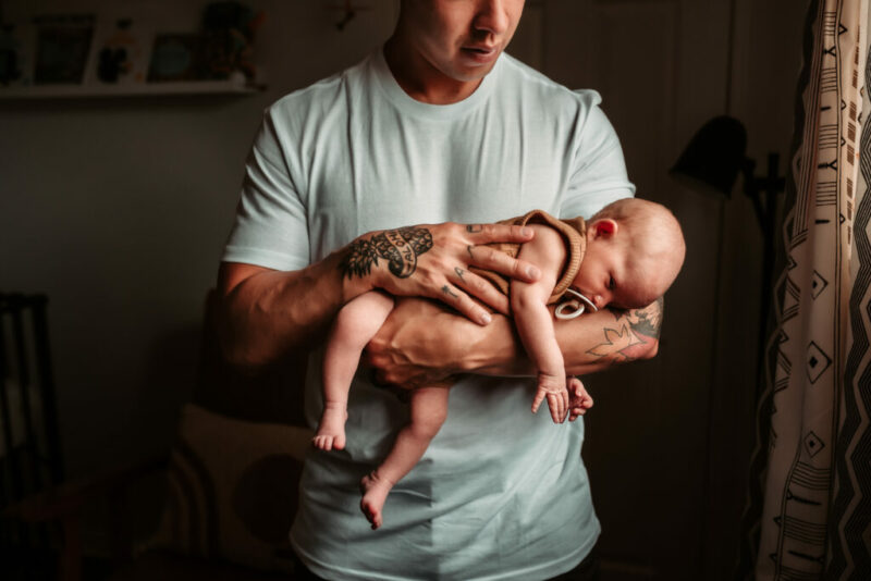 Father holding his new baby during an in-home newborn session. 