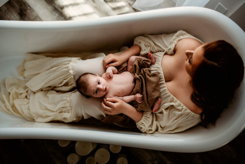 Mother holding her newborn baby in a bathtub during a newborn photography session in Bowmanville